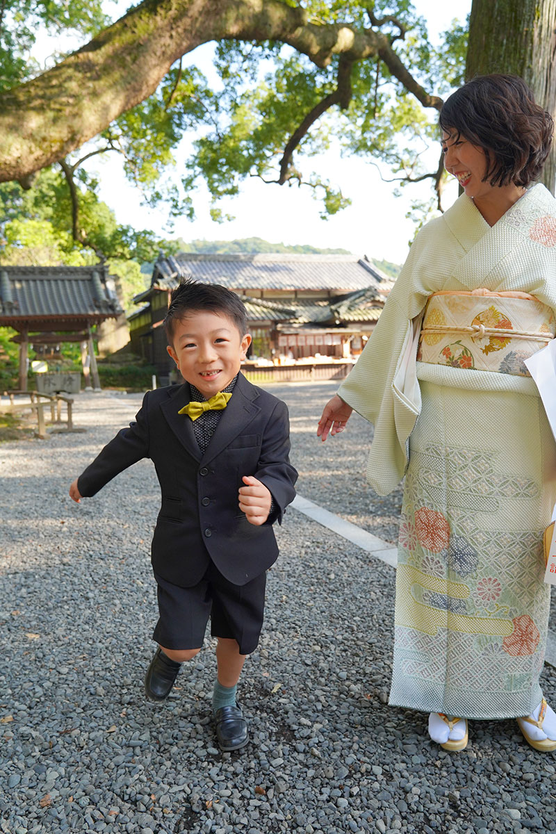神社で笑顔で走る男の子と母親