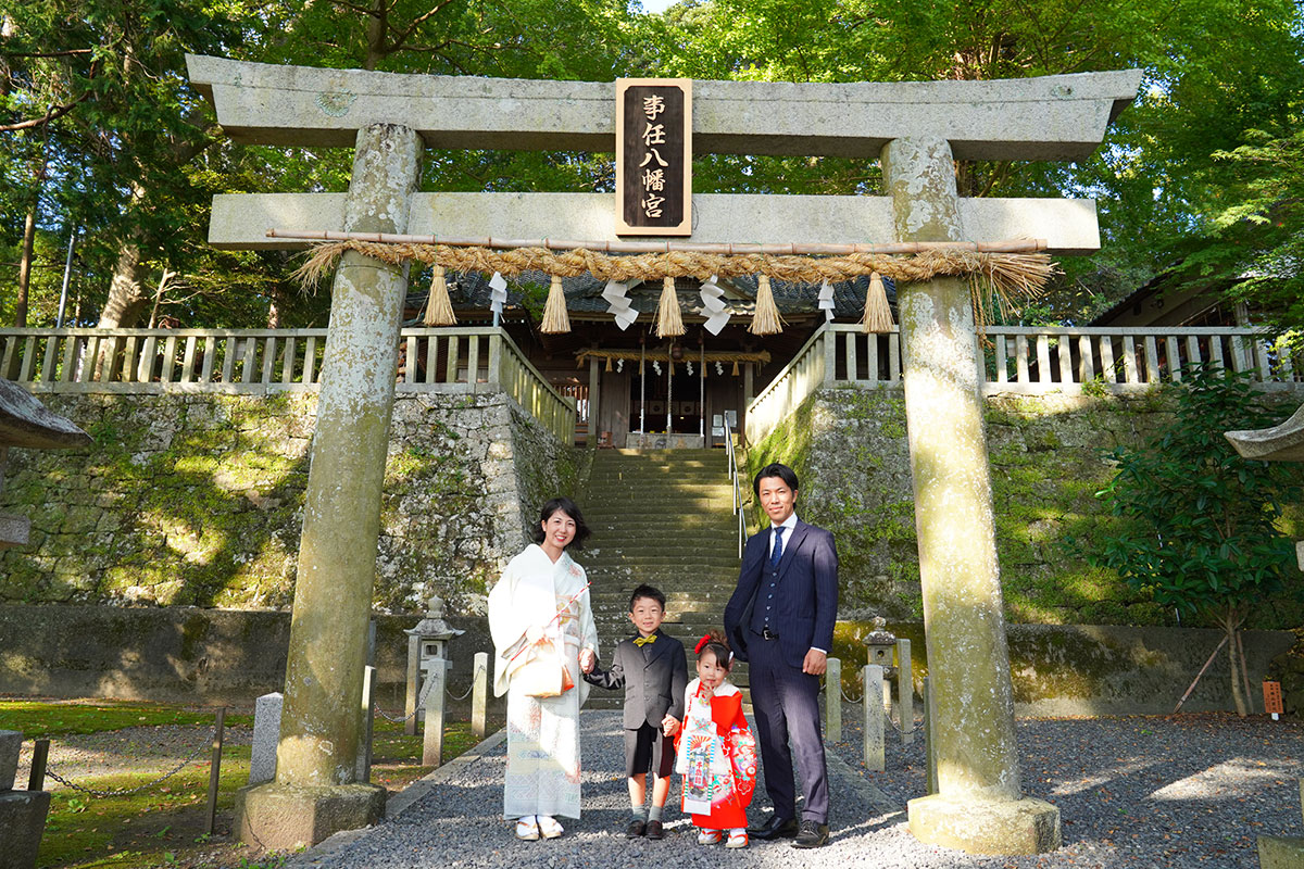 神社の鳥居の前に立つ七五三の家族